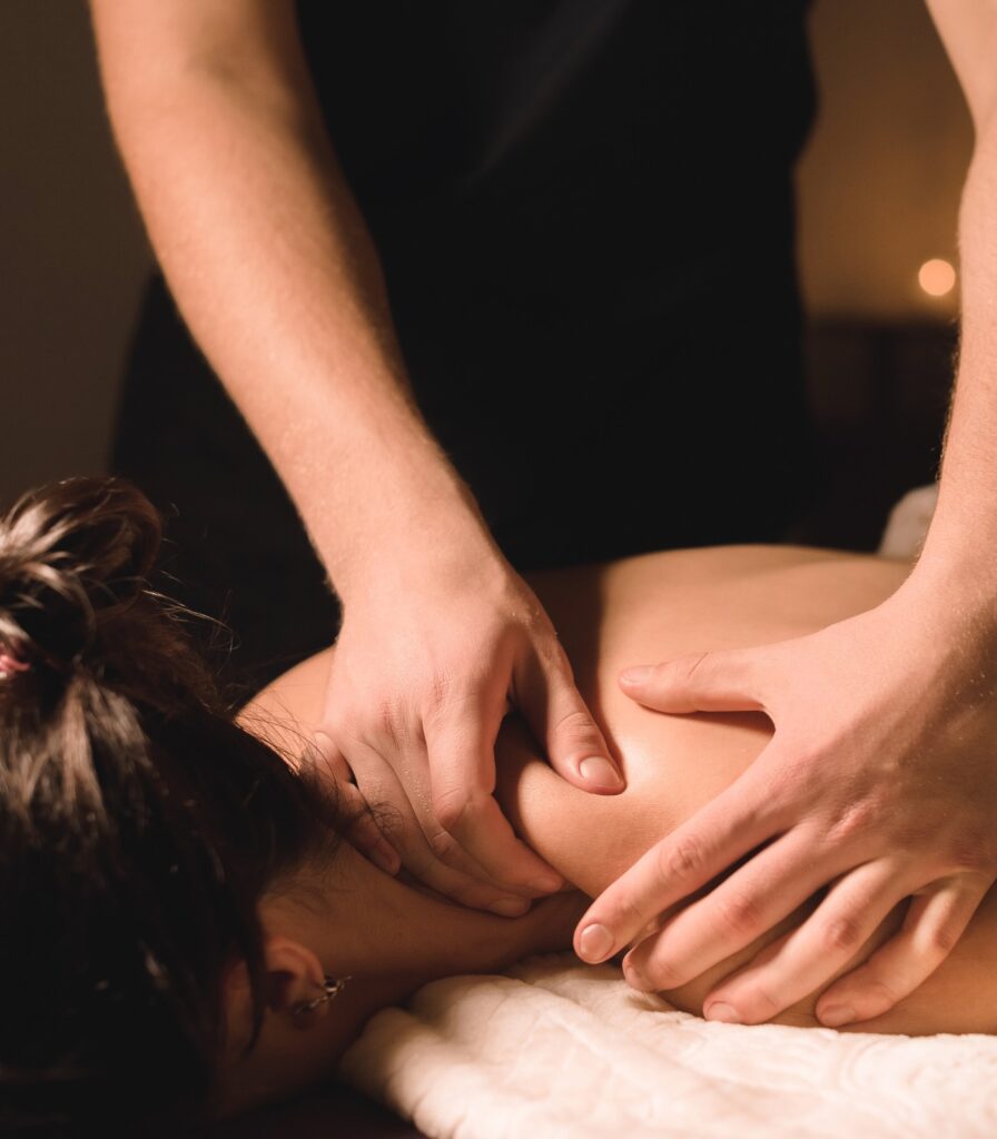 Wellnessmassage bei gedämpftem Licht – Mann behandelt junge Frau
