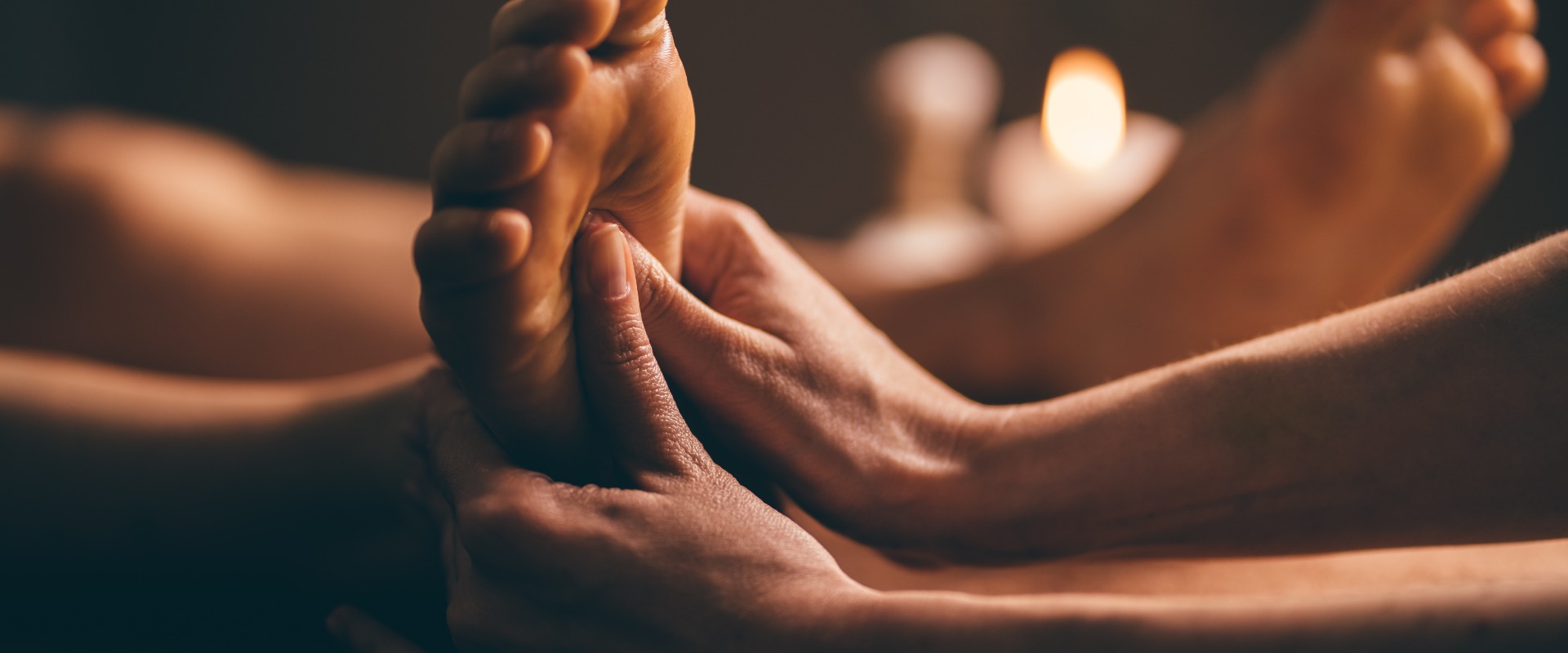 Professionelle Fußmassage in Großaufnahme. Authentische Aufnahme einer luxuriösen Spa-Behandlung. Charmantes Licht. Geringe Tiefenschärfe. Stilisiert und farbig.