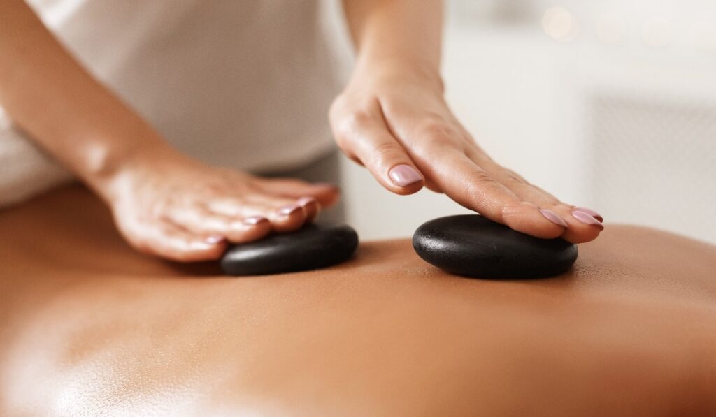 Masseur doing back hot stone massage, closeup